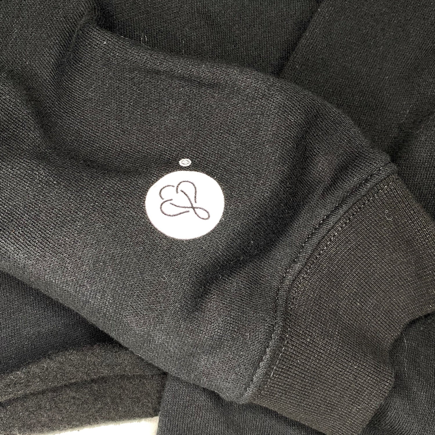 Showcasing the sleeve of the BIG LOViE CREWNECK SWEATSHIRT BLACK with logo detail and soft fabric texture.
