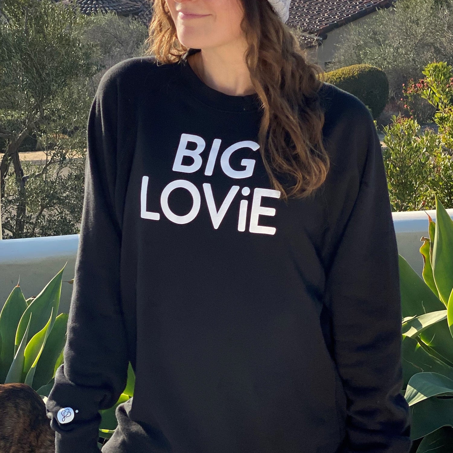 Woman wearing BIG LOViE CREWNECK SWEATSHIRT BLACK, showing bold text design in a cozy outdoor setting.